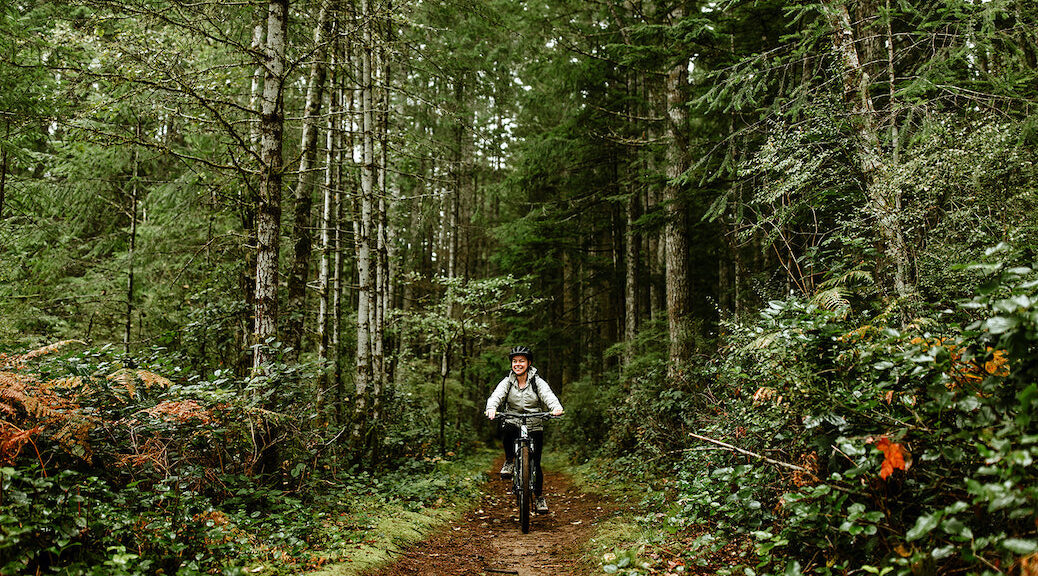 Woman cycling through the forest on one of Cortes Island's trails