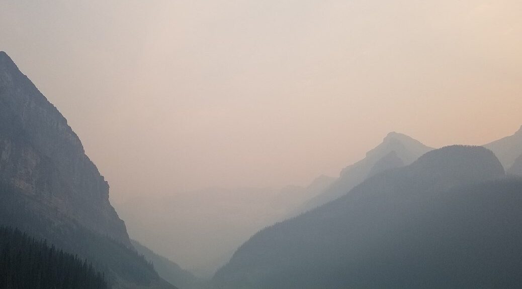 smoke from wildfire over a lake in the mountains