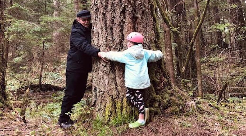 An old man and young girl hugging a tree