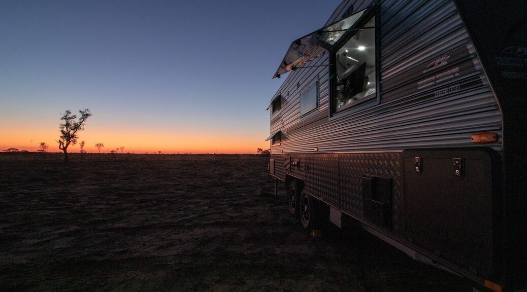 Side of an RV set against a desert sunrise
