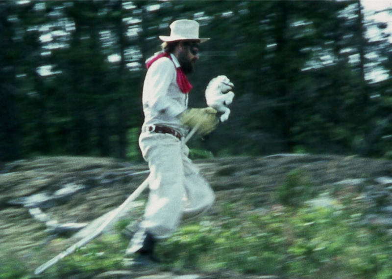 Man dressed in a white cowboy suit riding a hobby horse