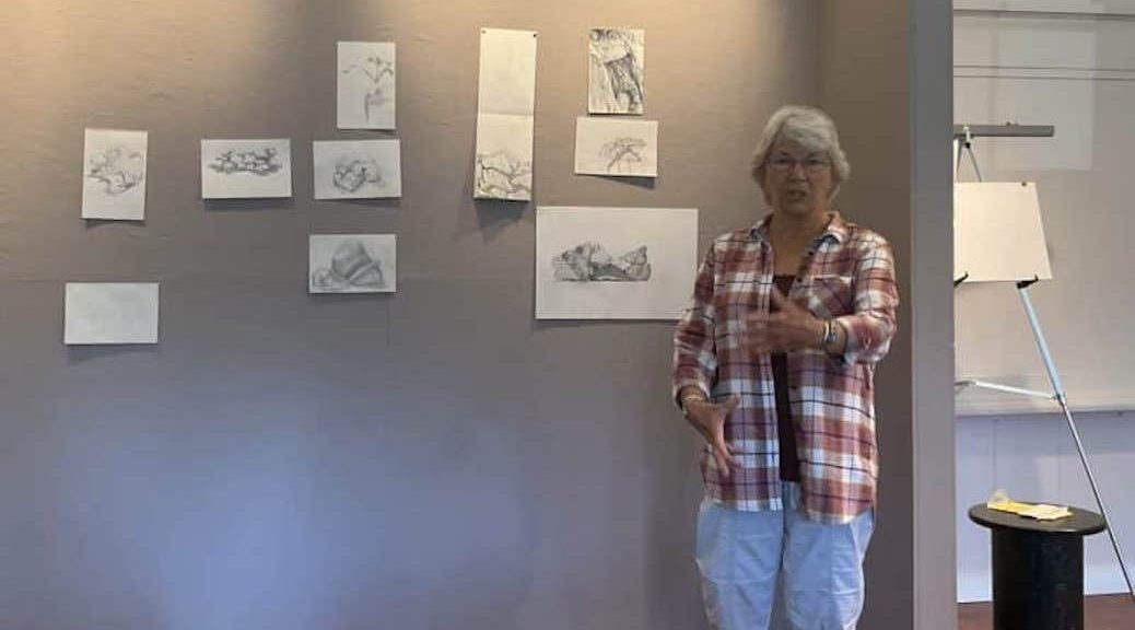 Woman standing in front of a display of 10 nature sketches