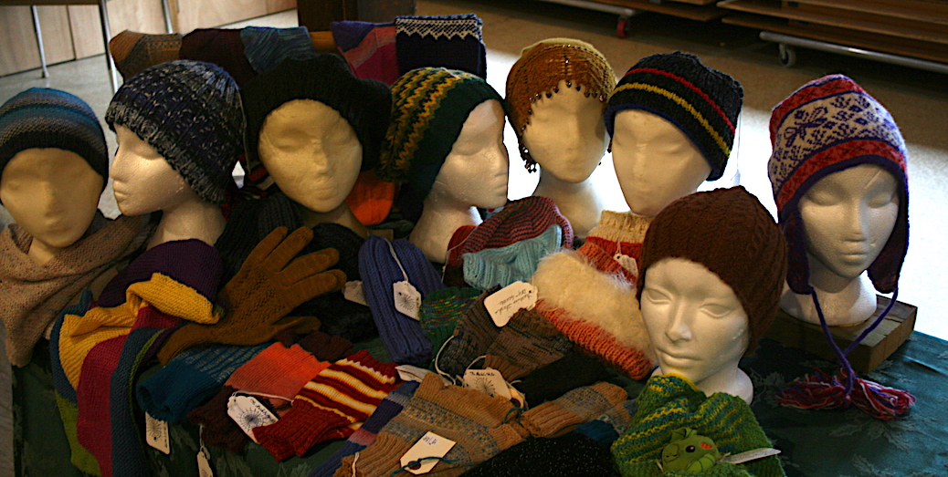 Toques, scarves and hmittens displayed on a table.