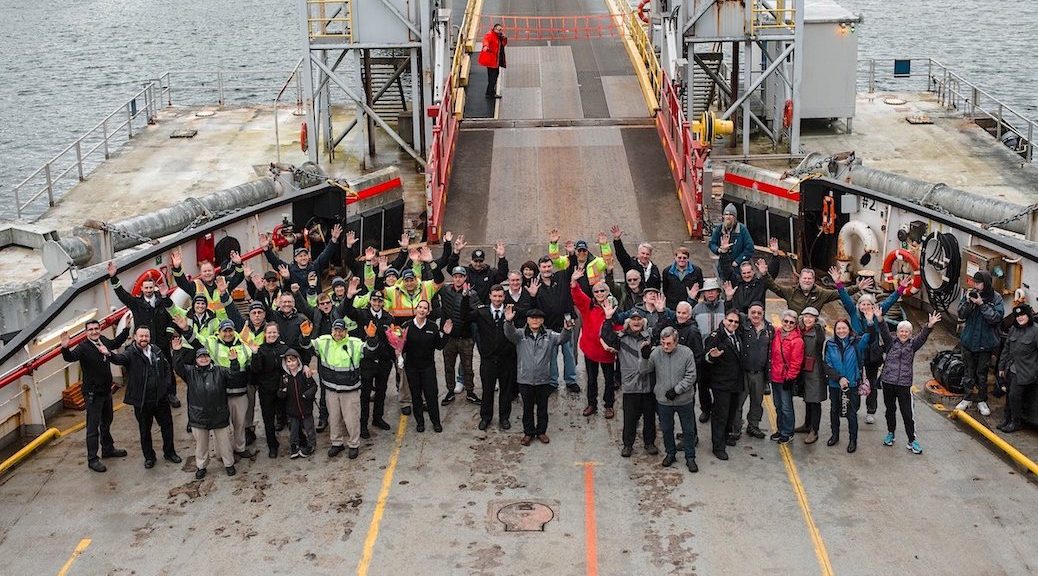 A group of people standing in front of the off ramp of a BC Ferry