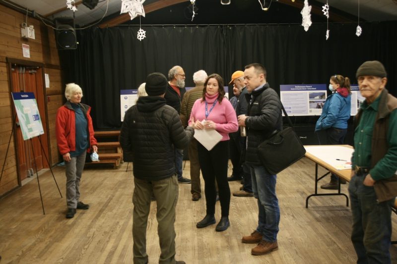 People gathered around talking in a hall, surrounded by placards