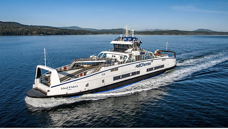 A modern looking ferry sails past an island