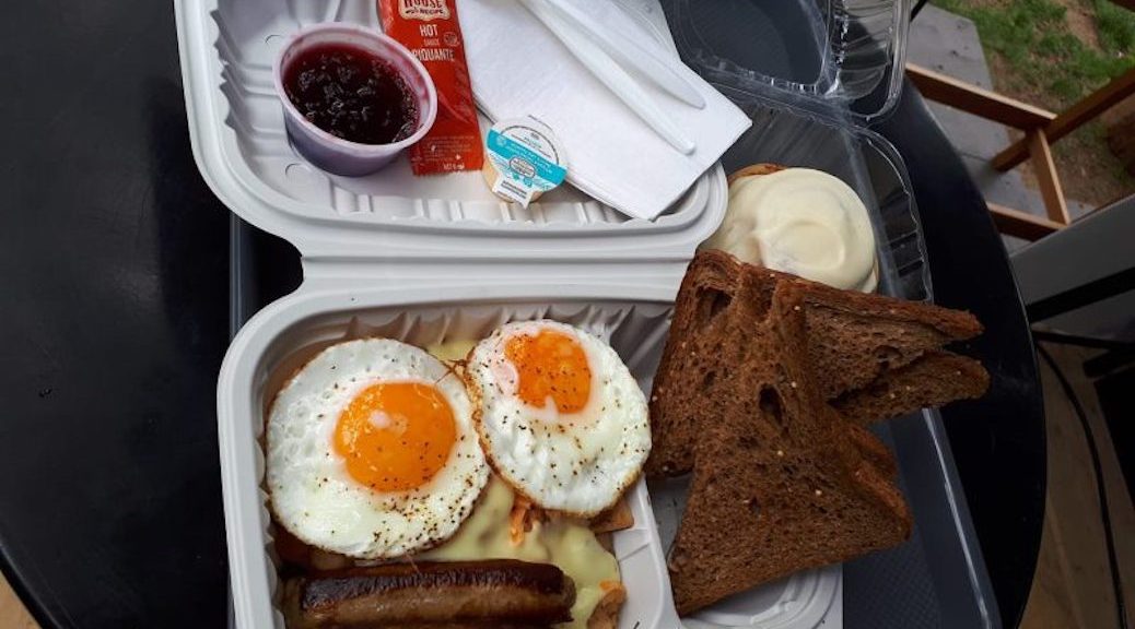 Bacon and eggs with toast and jam in a takeout container