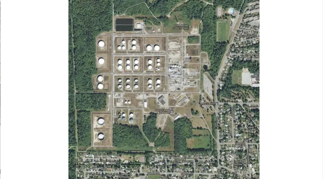 An aerial view of rows of circular propane silos beside a residential area