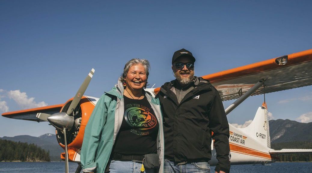 A man and woman standing in front of an airplane