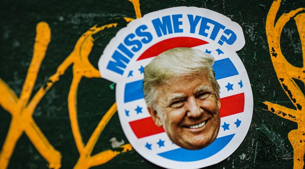 Image of Donald Trump imposed on red white and blue stripes. The words 'miss me yet' appear over his head