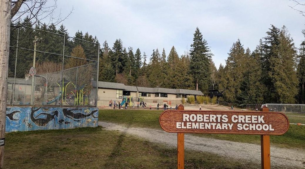 Lookinf across a field at an elementary school. A wooden sign says Robert's Creek Elemenatry School