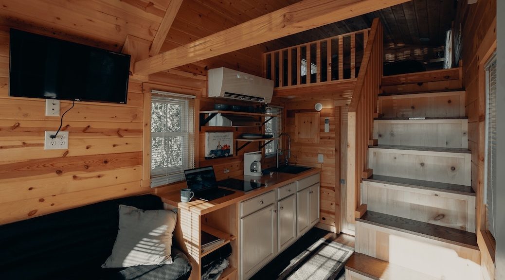 a tiny kitchen with stairs leading up to a lofty