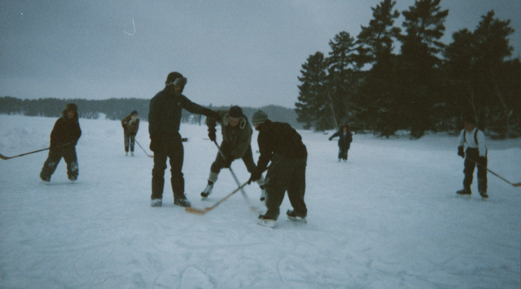 The face-off, as 8 people play hockey on a frozen pond