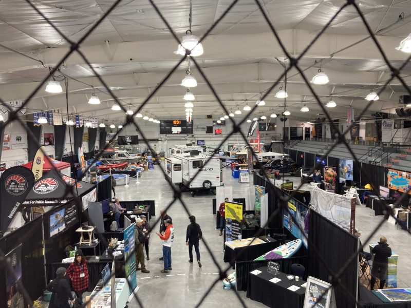 Looking through a wire mesh to a large exhibition halls filled with booths and people