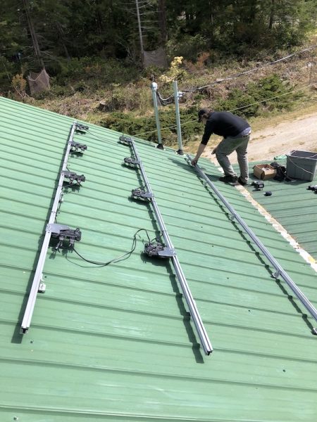 Man on roof beside the racking of a solar installation