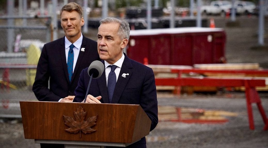 Man in a suit standing behind podium, another man looks on