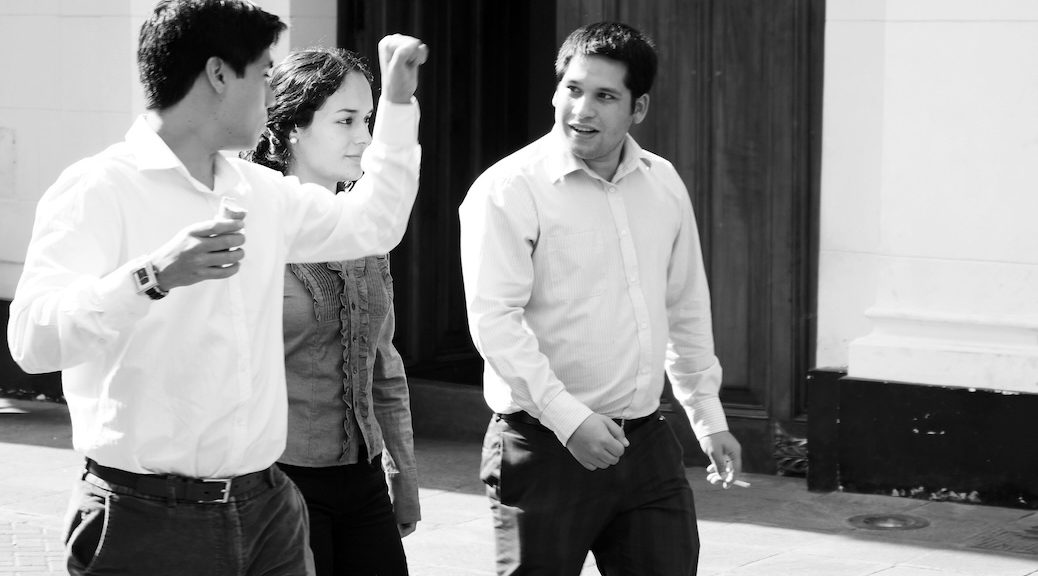 Two males assume aggressive postures, one with his fists in the air. There is a female between them.