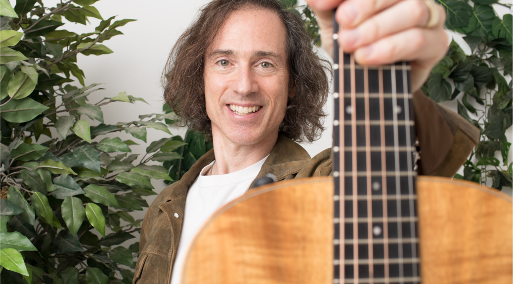 Mark Winters holding up his guitar