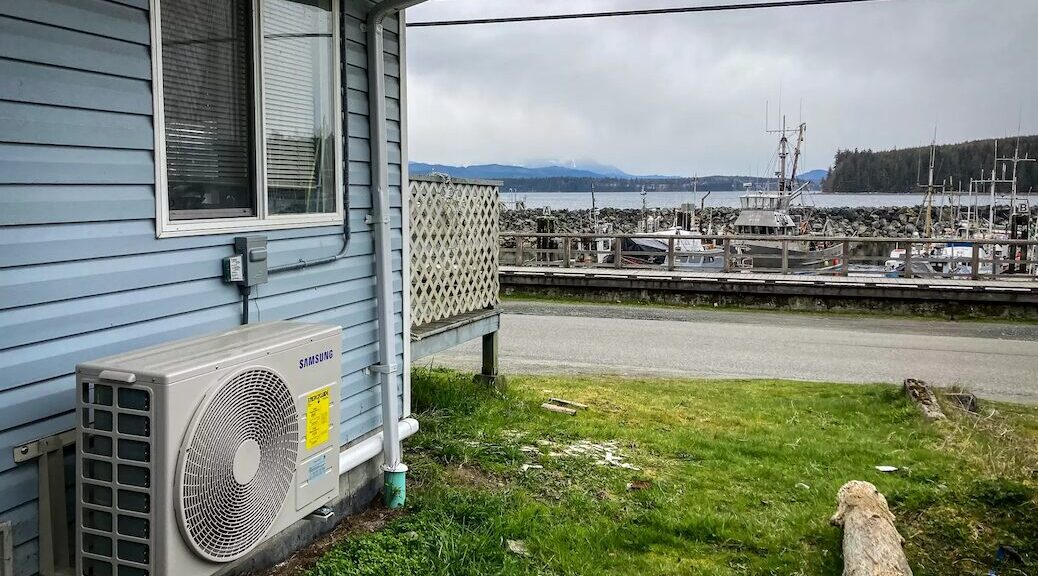 Heat pump, installed with EcoTrust Canada's help, sitting on the exterior of a house overlooking the ocean