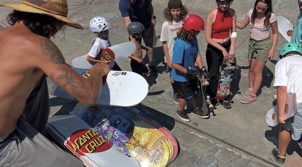 Two adults with 8 children with skateboard in a skate park