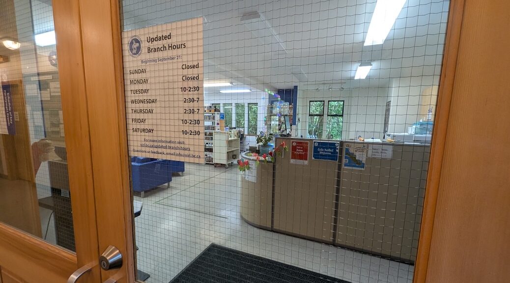 Looking in through a glass window to the front desk of the Cortes Island Public Library