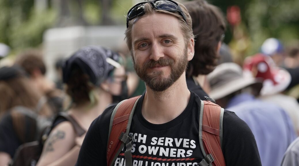 Smiling bearded man in the midst of a crowd