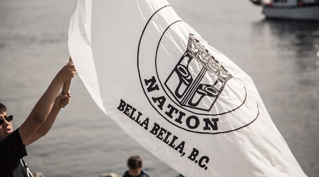 INdigenous man hoists the flag of Heiltsuk Nation