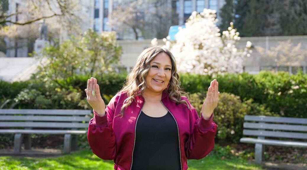 Smiling Indigenous woman hold her hands apart as if emphasizing the size of something