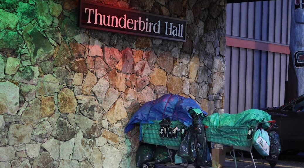 shopping cart filled with belongings and several Naloxone overdose kits is parked outside the Thunderbird Hall
