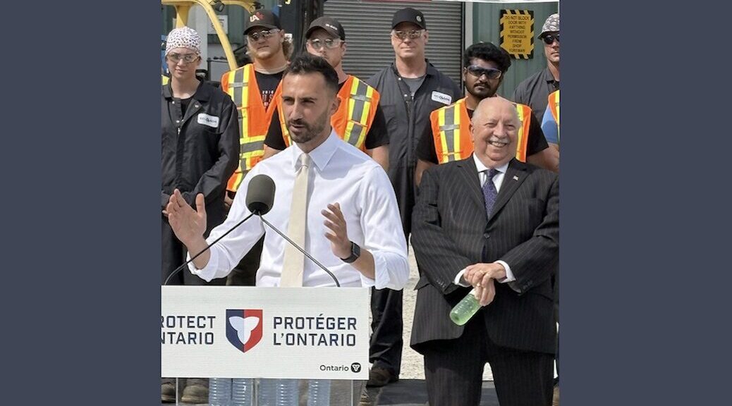 Man dressed in white adressing crowd from behind a podium that says 'protect Ontario'